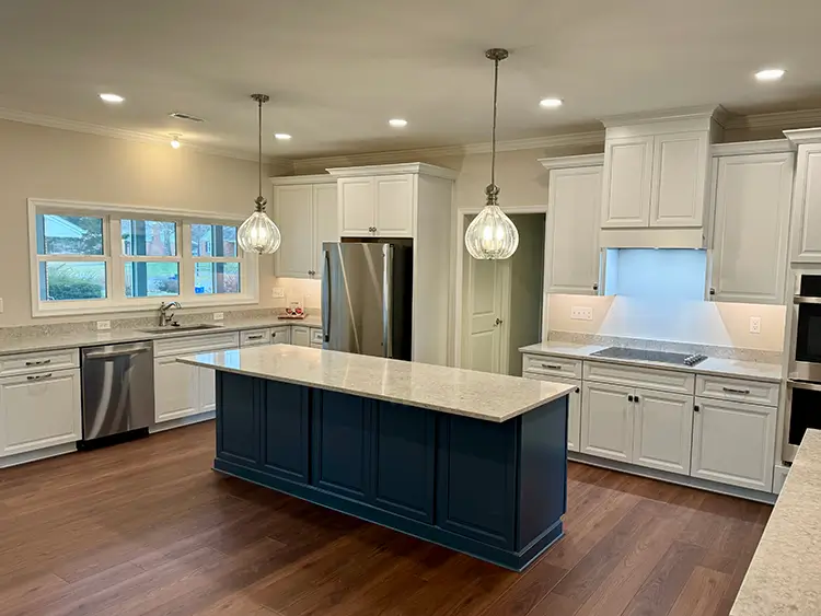 Interior photo of a kitchen with a marble kitchen center countertop and two pear shaped lights hanging from the ceiling.