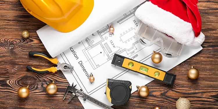 Blueprint covered in christmas decorations and construction tools